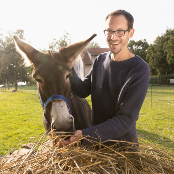 Porträt von Benjamin Raschke auf Bauernhof mit Esel